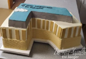 Dreidimensionale Torte in Form eines Landratsamts-Gebäudes, mit blauer Dachfläche und der Aufschrift "Unser Landratsamt der Zukunft!".