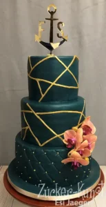 Dreistöckige Hochzeitstorte in Dunkelgrün (Petrol) mit goldenen geometrischen Linien und Anker-Topper. Eleganter moderner Stil. Zucker-Kunst Esi Jaeger.