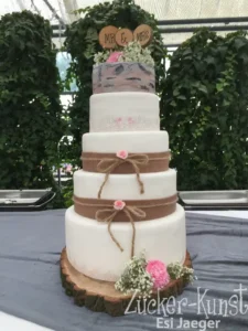 Mehrstöckige Hochzeitstorte (5-stöckig), rustikal: Baumstamm-Unterlage, braune Schleifen, Spitzenband und Mr & Mrs Holz-Topper. Zucker-Kunst Esi Jaeger.