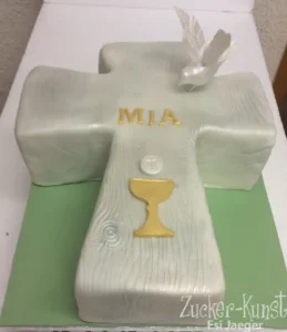 Torte in Form eines Kreuzes mit Holz-Optik, gekrönt von einer Taube, Kelch und Hostien-Symbol.