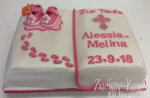 Torte in Buch-Form zur Taufe, in Pink und Weiß, dekoriert mit Babyschuhen, Fußspuren und Kreuz.