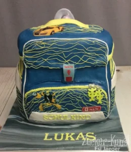 Torte in Form eines blauen Schulranzens, verziert mit einem gelben Sportwagen und einem Transformer-Motiv.