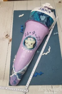 Glitzernde Torte in Form einer Schultüte in Lila, für ein Mädchen zur Einschulung.