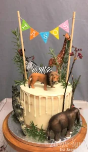 Moderner Drip Cake (weiße Glasur) mit Dschungel-Dekoration und Tierfiguren für einen Jungen-Geburtstag.