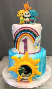 Coole Torte mit Regenbogen und Wolken, gekrönt von bunten Tierfiguren, ideal für kleine Jungen.