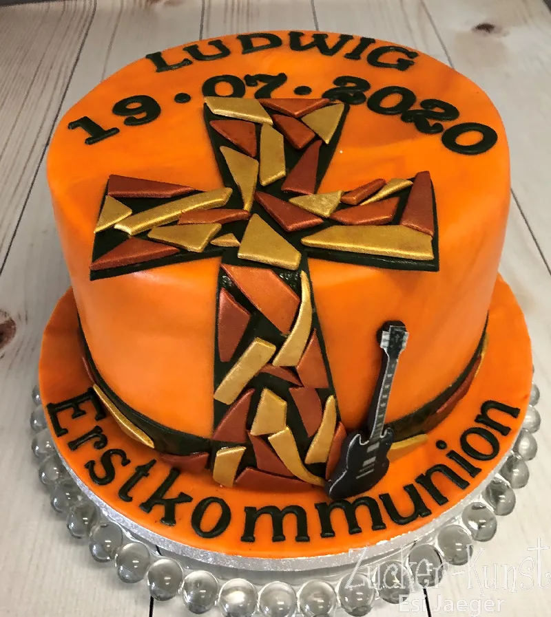 Runde orangefarbene Kommunionstorte mit einem Mosaik-Kreuz aus Gold und Bronze, Datum und einer kleinen schwarzen E-Gitarre.