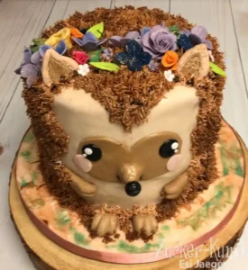 Runde Igel Torte mit Fell aus Kokosflocken und einem bunten Blumenkranz, perfekt für einen Mädchen-Geburtstag.