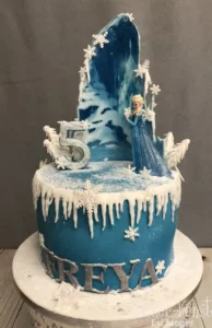 Eiskönigin Torte mit Elsa-Figur, Eisscholle und der Zahl 5, personalisiert und in Blau-Weiß.