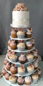 Elegante Kombi-Hochzeitstorte: Einstöckiger Fondantkuchen mit Rosen, umgeben von Cupcakes in Rosé- und Cremetönen auf 5-stöckiger Etagere.