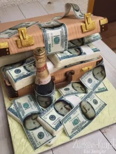 Zweistöckige Torte in Form zweier aufeinandergestapelter beiger Aktenkoffer, verziert mit Bündeln essbarer 100-Dollar-Scheine und einer Champagnerflasche.