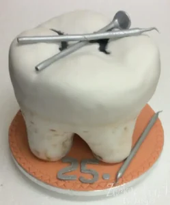 Dreidimensionale Torte in Form eines Backenzahns mit silbernem zahnmedizinischem Instrumentarium und der silbernen Zahl 25 auf dem Tortenbrett.