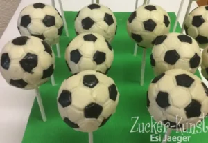Viele Cake Pops in Form von Fußbällen auf einem grünen Display-Hintergrund.