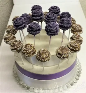 Elegante Cake Pops in Lila und Braun, dekoriert mit feinen Streuseln auf einer zweistöckigen Etagere