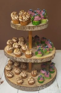 Cupcake-Etagere für die Party: Dreistöckige Präsentation von Schoko-Cupcakes mit Karamell und Blaubeer-Cupcakes mit Minze auf Baumscheiben-Ständern.