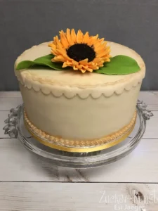 Geburtstagstorte Frau: Cremeweiße Torte mit großer Sonnenblumen-Deko.