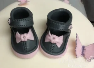 Zuckerfiguren: Babyschuhe mit rosa Schleifen.