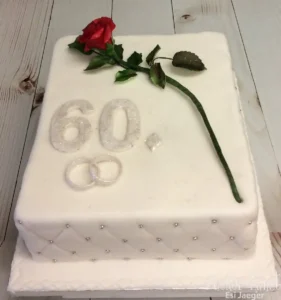 Eckige Torte zur Diamantenen Hochzeit in Weiß mit silbernen Ringen, der Zahl 60 und einer roten Rose.