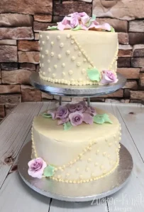 Allergiegerechte Torte zur Goldenen Hochzeit mit filigranen Punkten und rosa Zuckerblumen auf zwei Etagen.